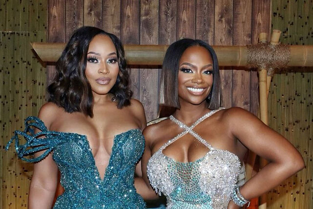 Kandi Burruss and Monyetta Shaw posing together in formal looks in front of a portugal inspired set.
