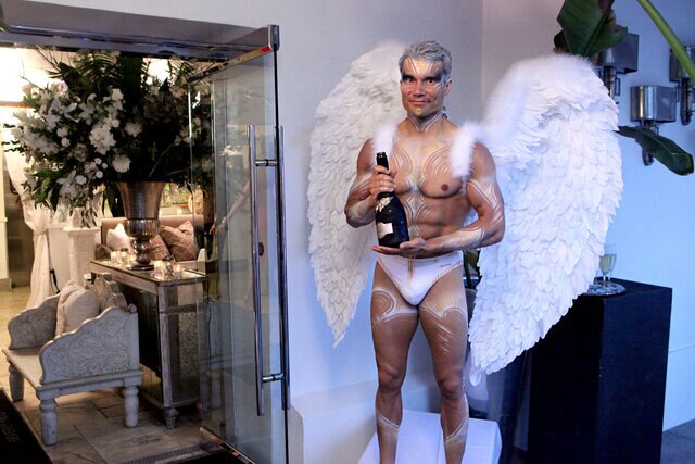 A server in an angel costume serving champagne at Villa Blanca.
