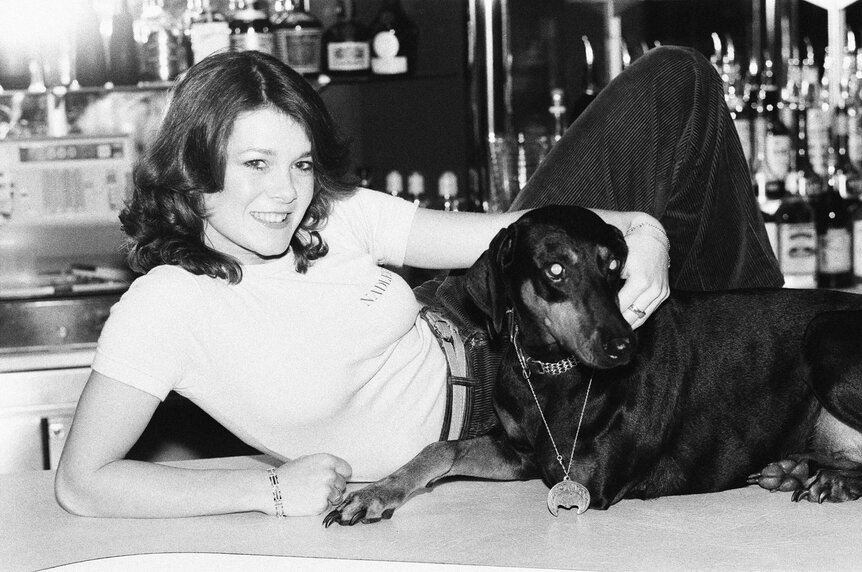 Lisa Vanderpump at 17 sitting on a bar counter with a doberman pinscher.