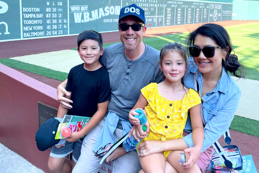 Crystal Kung Minkoff sits with her husband and their two kids at a baseball game.