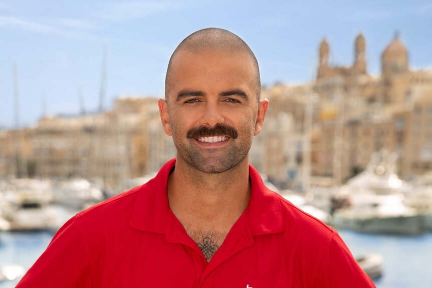 Storm Smith outside at a marina wearing a red polo shirt.