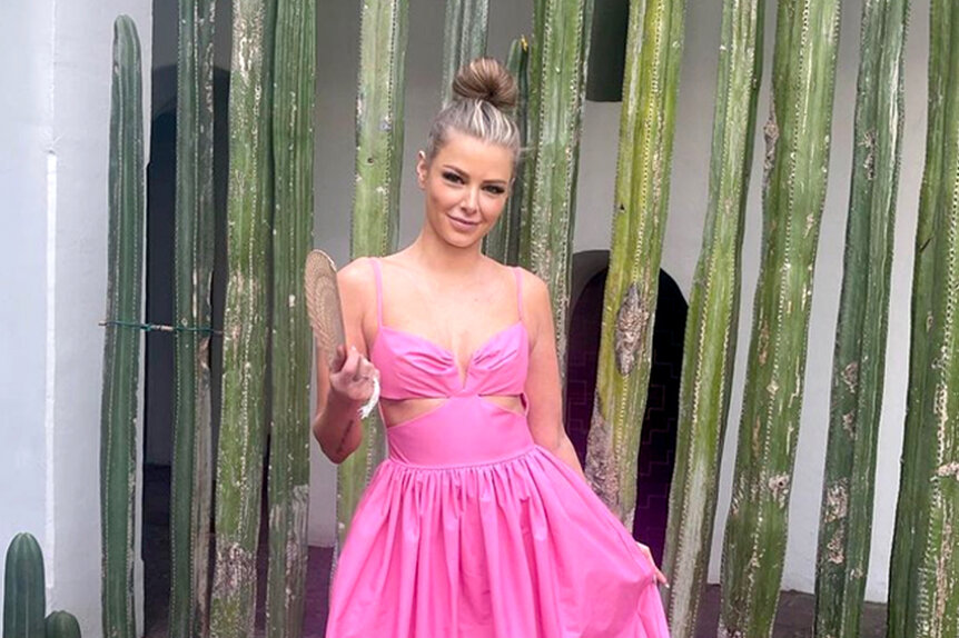 Ariana Madix wearing a pink dress posing in front of cacti