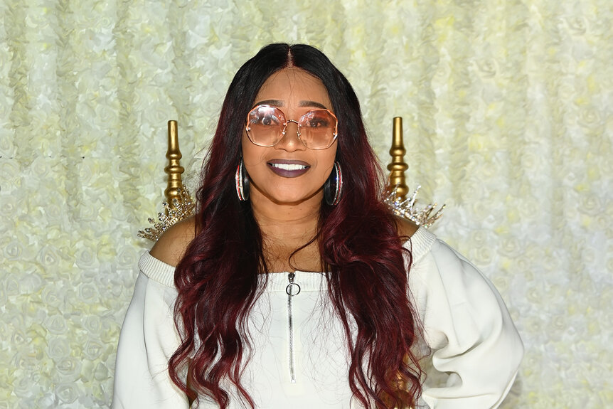 Lelee Lyons of SWV wearing glasses and a white dress.