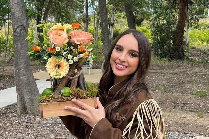 Alexia Umansky holding a plant outdoors.