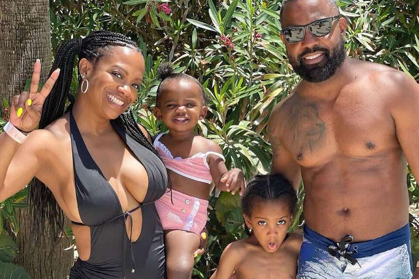 Kandi Burruss gives a peace sign in an Instagram photo wearing a bikini with her husband Todd Tucker and children Blaze and Ace