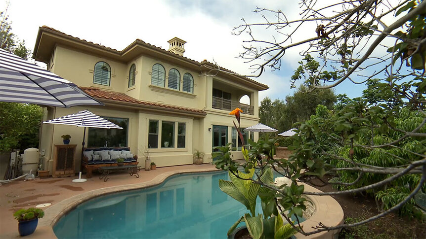 Taylor Armstrong’s backyard with a pool, umbrellas, and foliage.