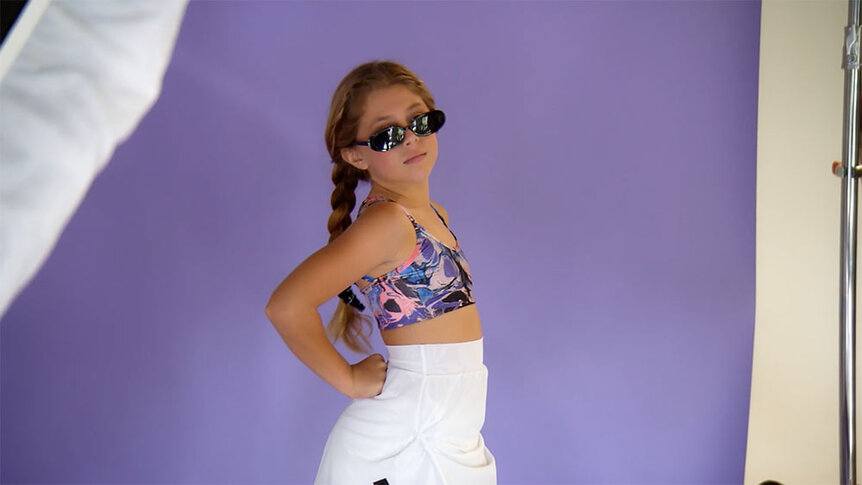 Annabelle modeling in a colorful top, a white skirt, and black sunglasses.