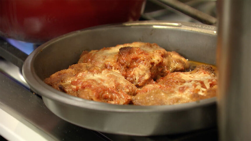 Chicken parmigiana in a pan.