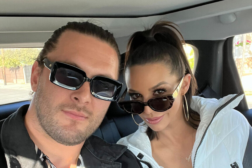 Scheana and Brock pose together wearing sunglasses in a car.