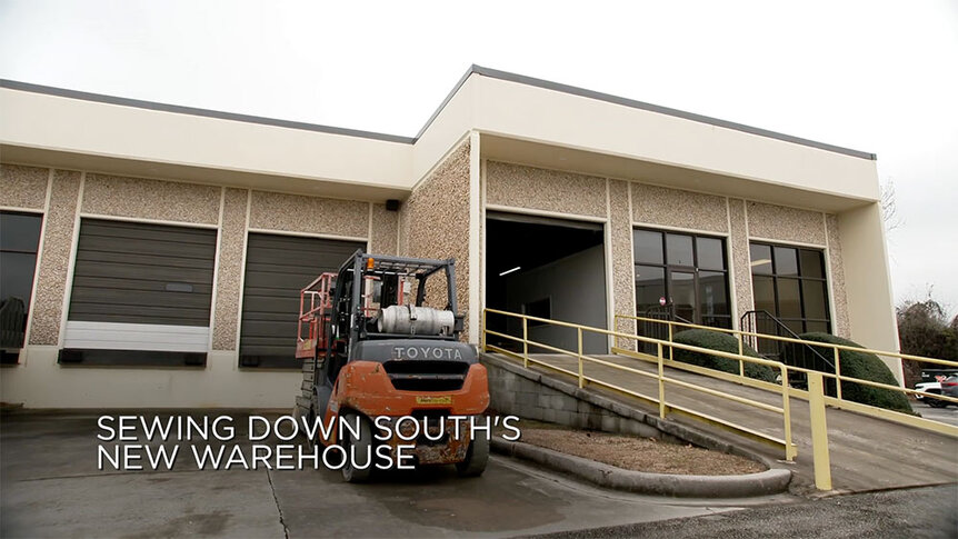 The exterior of Craig Conover's new warehouse for Sewing Down South with a tractor parked in front.