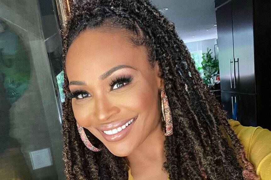 Cynthia Bailey smiling in a yellow outfit.
