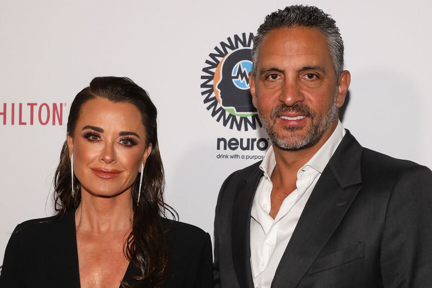 Kyle Richards and Mauricio Umansky posing together in front of a step and repeat in formal attire.