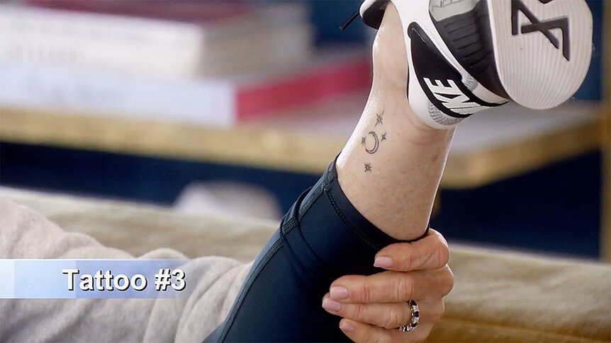 Kyle Richards showing Mauricio Umansky a moon and star tattoo on the side of her ankle.