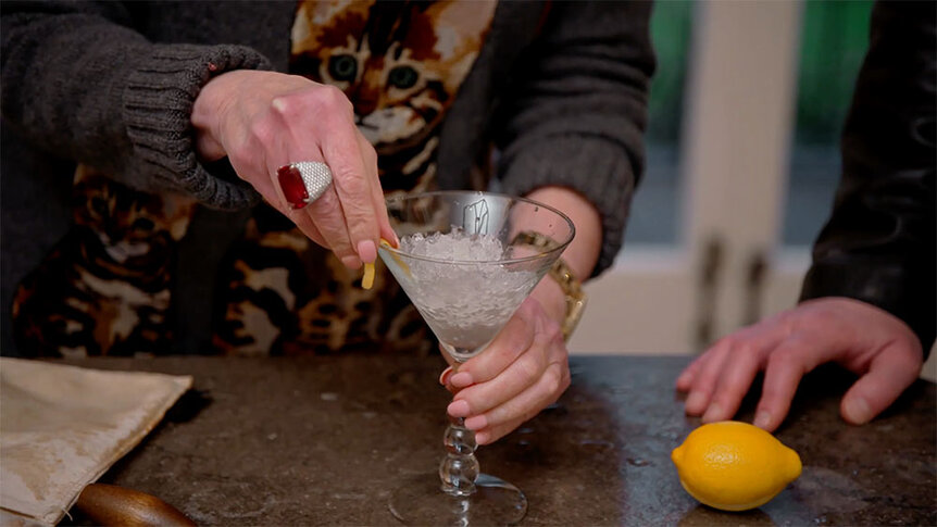 Patricia Altschul rubbing a lemon rind on the rim of a martini glass.