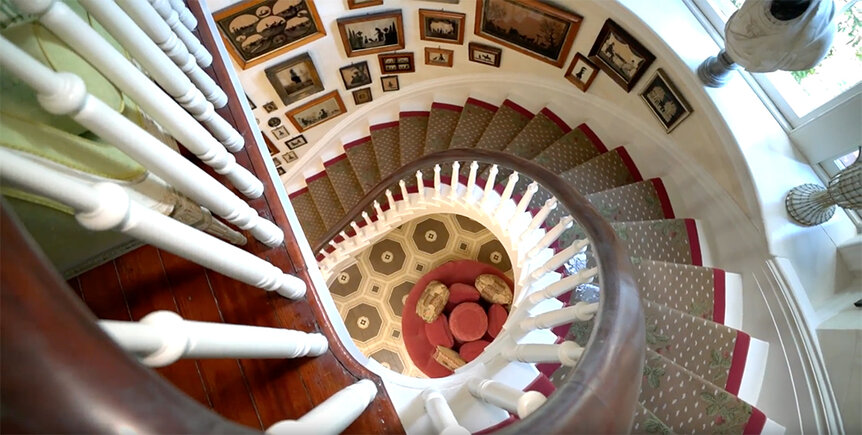 Patricia Altschul's stairs in her estate with art and photos on the wall.
