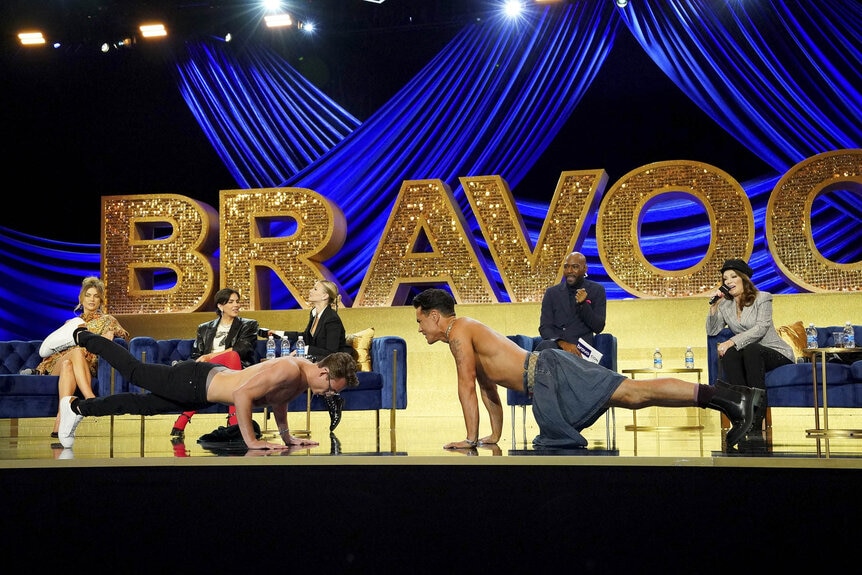 Tom Sandoval and James Kennedy having a pushup contest on stage during a panel at BravoCon 2023.