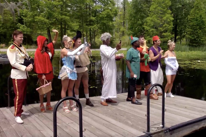 The cast of Southern Hospitality dressed up in fairytale costumes stand on a dock and take photos in Season 2 Episode 3.