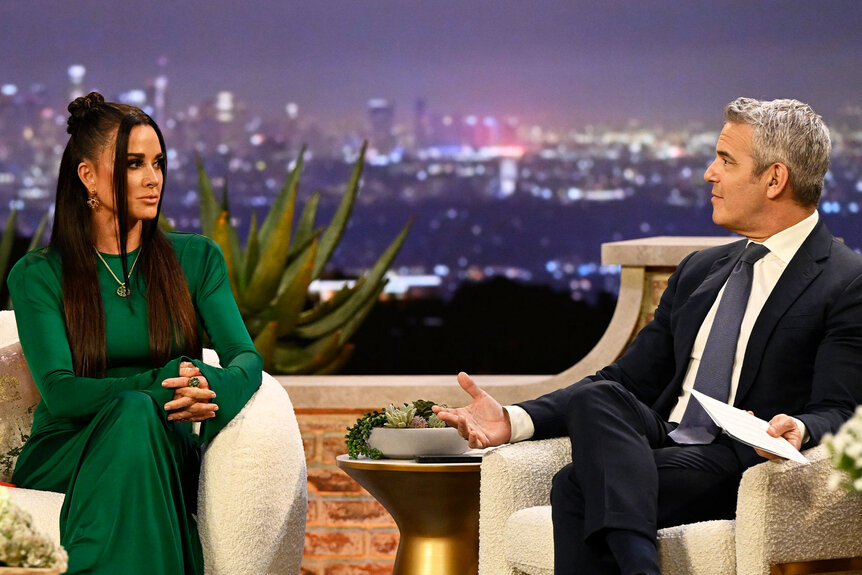 Kyle Richards and Andy Cohen talking together in front of a Beverly Hills themed set during the Season 13 Reunion.