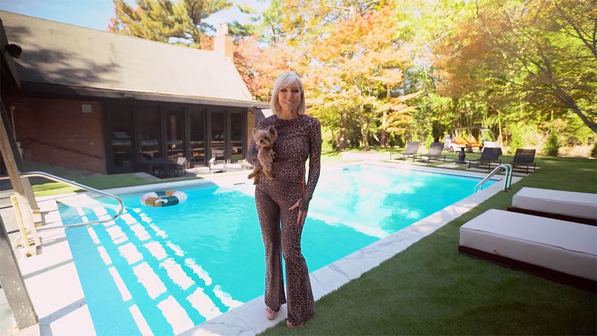 Margaret Josephs smiling while holding her dog standing in front of her backyard pool.